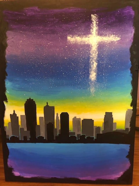 Skyline at Sunset Painting of a city skyline silhouette against a purple and orange sky with a glowing cross