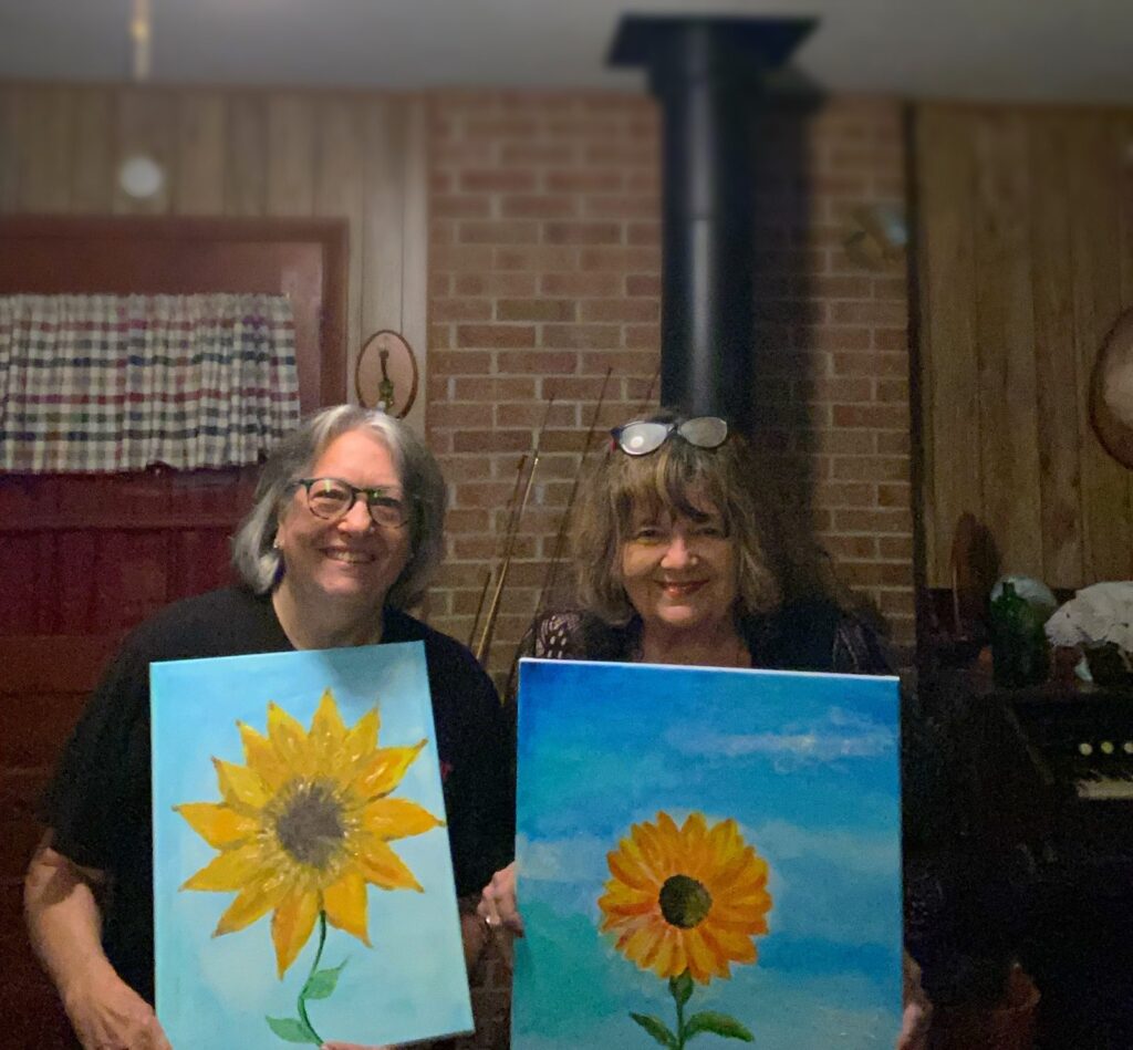 Art Class Sunflower Painting Retreat Participants Two smiling participants holding their completed sunflower paintings at the art retreat.