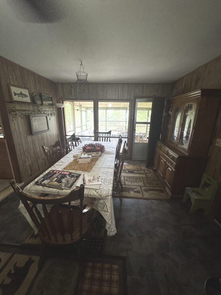 The Long Table in the Big House Long dining table with lace tablecloth, antique hutch, and screened porch beyond in the Big House.