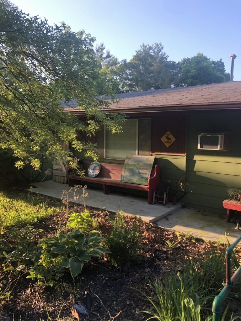 Fisherman's Haven — Summer Entrance Fisherman's Haven retreat exterior on a sunny summer morning with garden and porch bench.