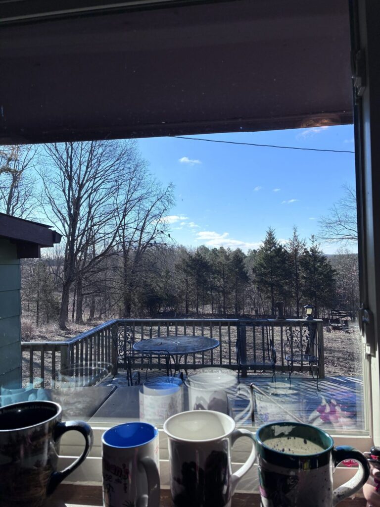 Morning Coffee at Fisherman's Haven Coffee mugs on a windowsill with a winter deck and countryside view at the retreat.
