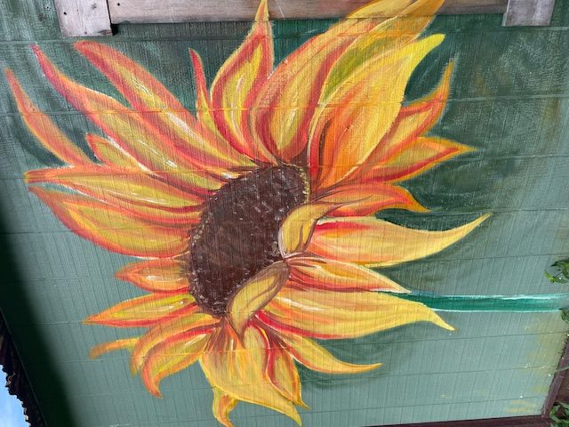Hand-painted sunflower mural on barn wood